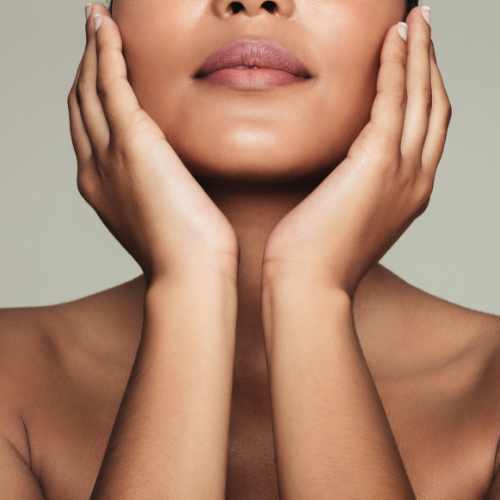 A woman touching both of her cheeks with her hands.