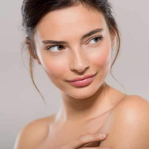 A woman looking to her side in front of a grey background.